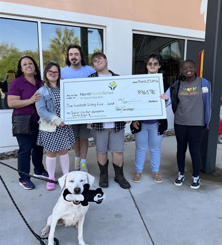 Four of the NFSSE Junior Civitan Club members and the Director Stacy presenting the check to the Humane Educator, Ms. Imani, outside the Adoption and Education Center with Lucy the dog. 