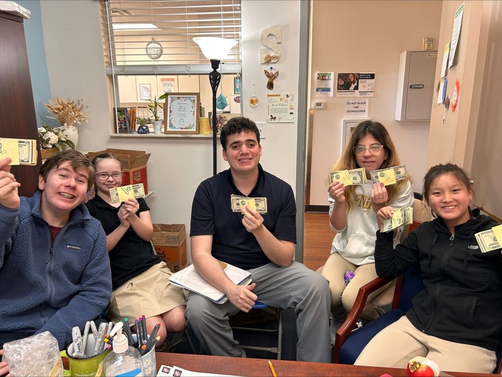 Pictured are various NFSSE's Junior Civitan Club members sitting around a table at school, counting the amount they made from candygram sales in 2024.